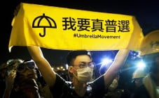 A pro-democracy protester holds up a banner on Lung Wo Road. Photo: EPA