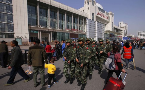 Armed Chinese police patrol near the exit of Urumqi's South Railway Station after last May's bomb and knife attack in Xinjiang, which left three people dead. Photo: Reuters 