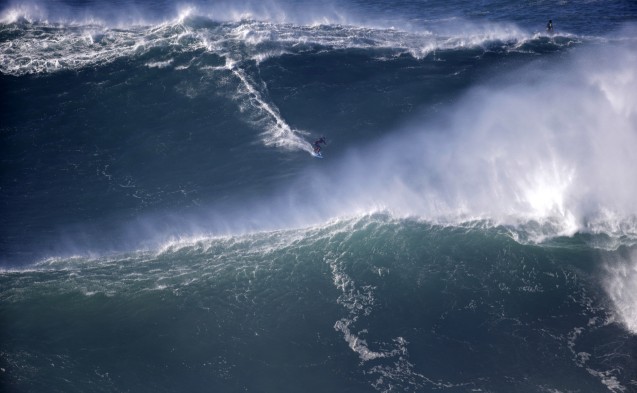 A surfer rides a big wave during a tow-in surfing session at the Praia do Norte or North beach, in Nazare, Portugal, Saturday, Nov. 29, 2014. A tow-in is a surf technique in which the athlete is towed into a large wave by a partner driving a jet-ski with an attached tow-line. (AP Photo/Francisco Seco)