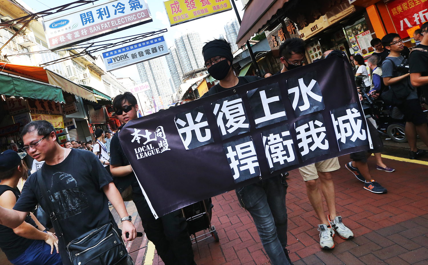 A protester walks along the road with a banner reading “restore Sheung Shui, fend off for our city.” Police presence was heavy with a ratio of at least one police officer to each protester. Photo: David Wong/SCMP