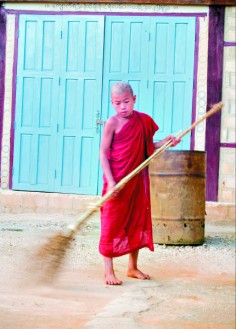 A young Burmese monk sweeps at his monastery.