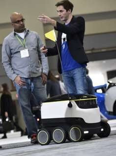 Henry Harris-Burland (right) explains the operation of the delivery robot. Photo: AFP