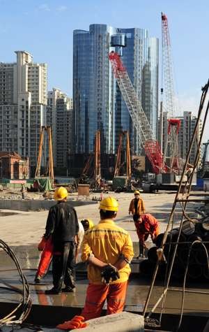 Labourers work at a new property development under construction on the busy Nanjing Road shopping street in Shanghai. Photo: AFP