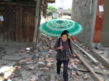 A woman walks through the rubble in Longmenxiang near the epicentre carrying a baby. Photo: Simon Son