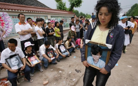 Parents hold portraits of their children at Wufu primary school, where 127 of 300 pupils died. Photo: Robert Ng