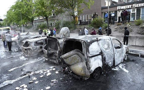 People inspect cars gutted by fire in the Stockholm suburb of Rinkeby. Photo: AFP