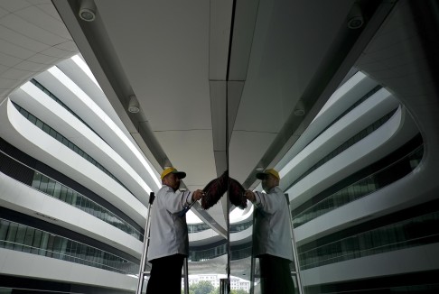 A cleaner wipes away dust in the futuristic Galaxy Soho building. Photo: AP