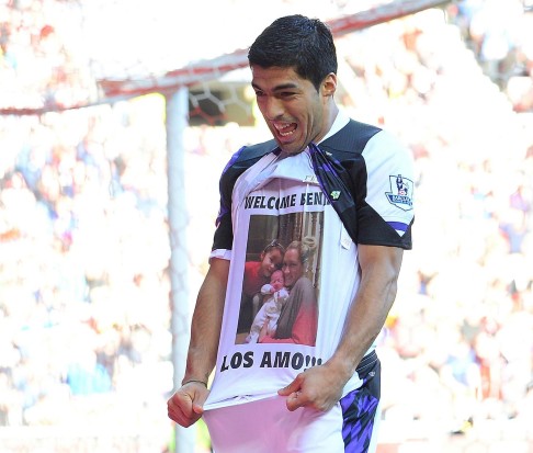 Suarez shows a picture of his new child with family as he celebrates. Photo: AFP