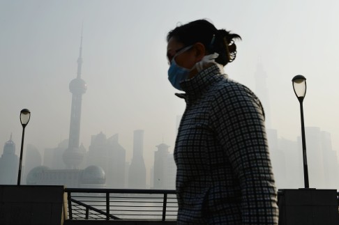 A woman wearing mask walks at the Bund, Shanghai, with Lujiazhui at back in heavy smog. Photo: China Foto Press 