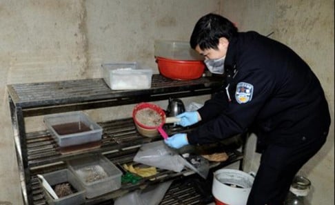 A police officer surveys drug-making equipment during the dawn raid in Boshe. Photo: SCMP/Handout