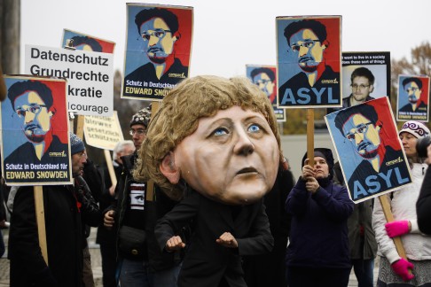 Protesters outside German parliament, one wearing a mask of Chancellor Angela Merkel, demand protection for Snowden in their country. Photo: AP