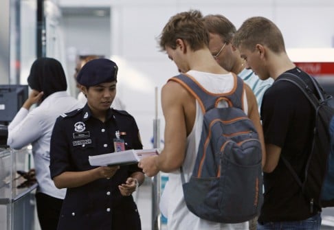 A customs officer checks the travel documents and passports of passengers at Kuala Lumpur International Airport. Photo: Reuters