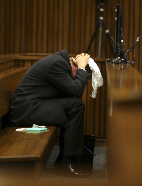 Oscar Pistorius covers his head with a handkerchief while hearing details of the shooting death of his girlfriend at his murder trial. Photo: AP