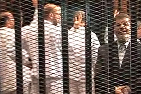 Ousted President Mohammed Morsi (right) speaks from the defendant's cage as he stands with co-defendants in a makeshift courtroom during a trial hearing in Cairo, Egypt in 2013. Photo: AP