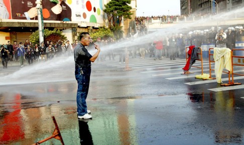 A protester refuses to leave the street despite being hit by police water cannon near the Cabinet compound in Taipei, 24 March 2014. Photo: EPA