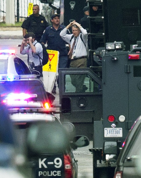 People hold their hands to their heads as they are escorted out of the building where a gunman was reported at the Washington Navy Yard in Washington on September 16, 2013. Photo: AP