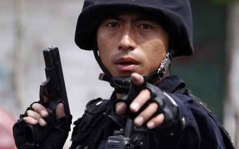A policeman waves a pistol during deadly ethnic riots in Urumqi, Xinjiang in July, 2009 that left 140 dead and 800 wounded. Photo: EPA 
