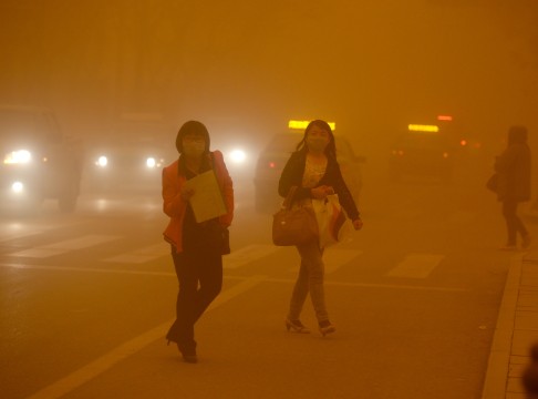 Women wear masks while walking in a sandstorm in Dunhuang. Photo: Xinhua