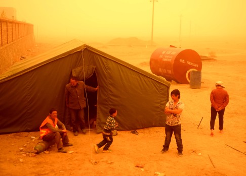 Building workers view a sandstorm on the outskirt of Guazhou, Jiuquan. Photo: Xinhua