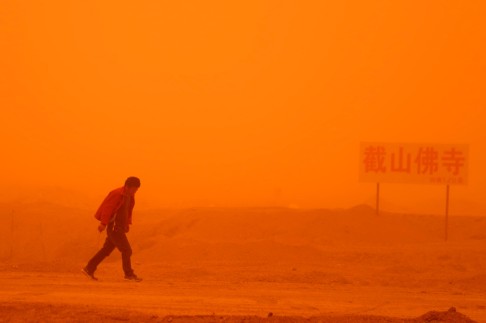 A man walks in a sandstorm on the outskirt of Guazhou, Jiuquan. Photo: Xinhua