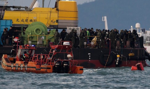 A diver gets out of the water as other rescue workers stand on a platform at the spot where the ferry sank. Officials have said volunteer divers are hampering the rescue effort. Photo: AFP