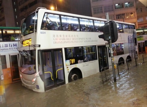 A number of buses were trapped by the rain, leaving stranded passengers to wade across flooded roads Photo: Martin Chan