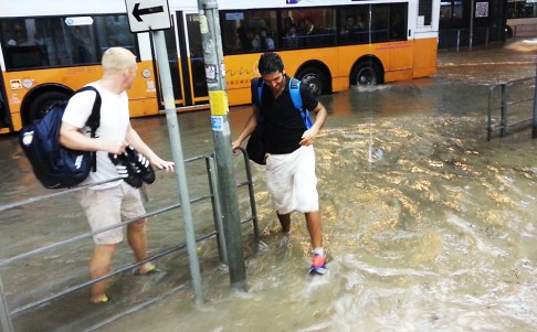 Passengers stand at a bus stop ankle-deep in water after the pouring rain causes flash flooding. Photo: Edmond So