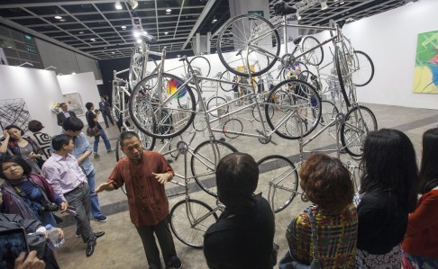 An art expert briefs art buyers on a sculpture made out of bicycles by dissident Chinese artist Ai Wei Wei entitled "Forever". Photo: EPA