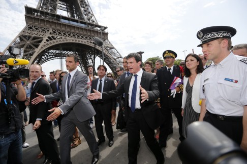French Interior Minister Manuel Valls (centre) and French police surrounded by journalists next to the Eiffel Tower in Paris in 2013 during a tour focused on security at the city's top tourist areas. Photo: Reuters