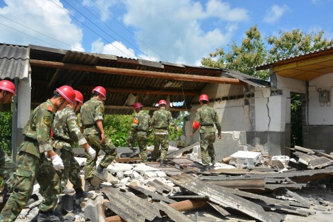 Rescuers check a damaged house in Yingjiang. Photo: AFP