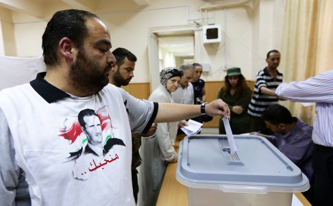 A Syrian man, wearing a shirt bearing President Bashar al-Assad's portrait, casts his ballot in presidential election on Tuesday at the Bassel al-Assad school polling station in central Damascus. Photo: AFP