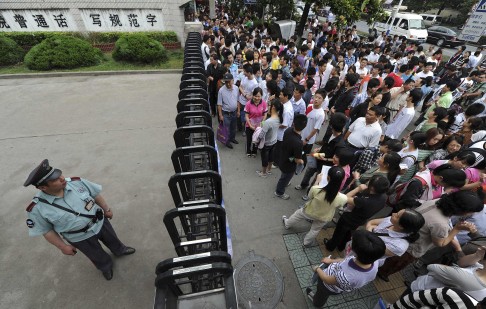 A security officer stands guard as students and their parents wait outside a school gate before the National College Entrance Exams in Hefei. Photo: Reuters