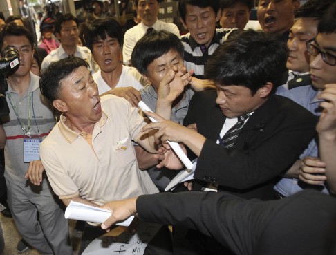 Family members of passengers aboard the sunken ferry Sewol struggle with a security officer, while attempting to attend the trial. Photo: Reuters
