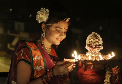An Indian girl lights an earthen lamp ahead of Diwali. Photo: AP