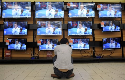 A man crouches in a TV store in Wuhan to watch a World Cup game between England and Uruguay. Sales of a government-run World Cup-related lottery reached 4 billion yuan by Saturday. Photo: Reuters
