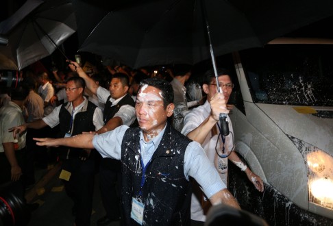 Security officers bear the brunt of protesters' paint bombs as they try to shield the car carrying Zhang Zhijun from the attacks in Kaohsiung. Photo: AFP