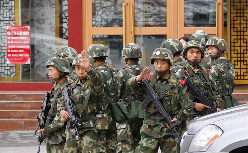 Paramilitary policemen gesture to stop a photographer from taking pictures as they stand guard after an explosives attack hit downtown Urumqi on May 23. Photo: Reuters
