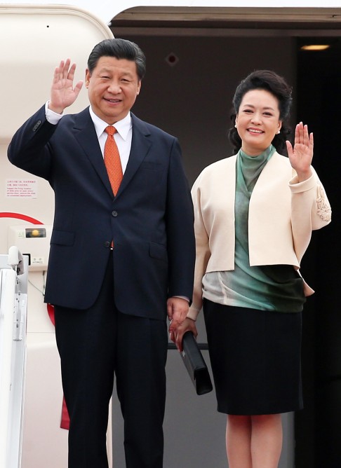 Xi Jinping (left) and his wife Peng Liyuan wave after arriving at Seoul Airport. Photo: EPA