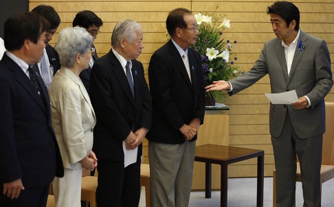 Japan's PM Shinzo Abe receives a petition from members of abduction issue groups in Tokyo on Friday. Photo: Reuters
