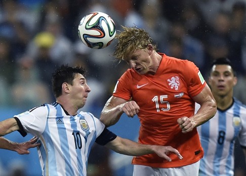 Dirk Kuyt goes up for a header with Lionel Messi. Photo: AP