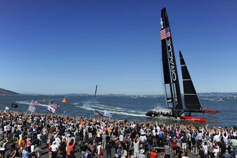 Fans cheer from the dock as Oracle Team USA crosses the finish line as they defeat Emirates Team New Zealand during the 16th race of the America's Cup Final in San Francisco last year. Photo: AFP