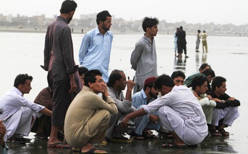 People wait to hear information about their missing family members at Karachi's Clifton Beach on Thursday. Photo: AP