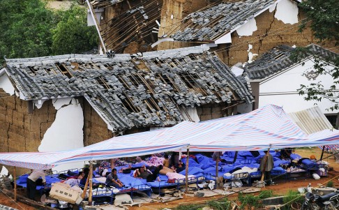 Villagers rest under a makeshift tent next to damaged houses after the deadly earthquake hit Longtoushan town. Photo: Reuters