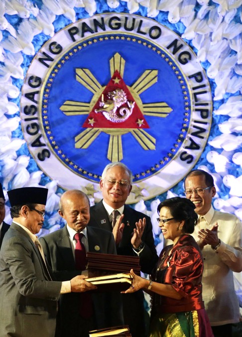 Philippine president Benigno Aquino III (right) and Malaysian Prime Minister Najib Razak (centre) witness the exchange of documents following the signing of a final peace agreement between the Philippine government and the Muslim rebel group inside the Malacanang presidential palace in Manila on March 27, 2014. Photo: EPA