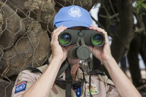 A Dutch UN officer stands in the Israeli-occupied Golan Heights, and watches through binoculars at the Syrian side after rebels took control of a key border crossing. Photo: AFP