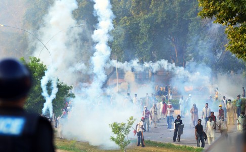Pakistani supporters of Imran Khan and Tahir ul Qadri stand amongst tear gas during clashes with security forces near the prime minister's residence in Islamabad. Photo: AFP