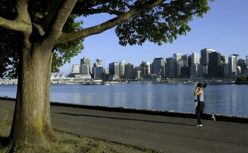 A jogger runs along the seawall in Stanley Park with the Vancouver city skyline in the background. Photo: Reuters 