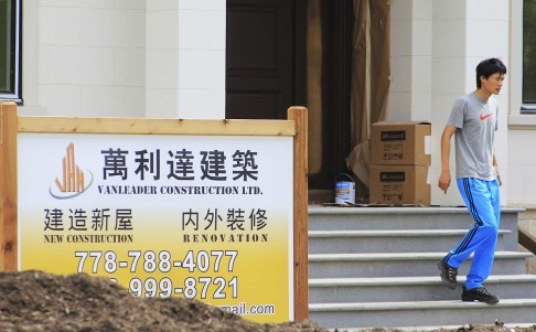 A man walks past a contractor's sign outside a mansion currently under construction in a Vancouver neighbourhood popular with Chinese buyers. Photo: Reuters