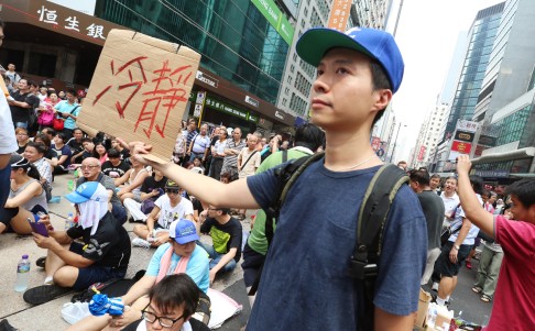 A protester holds a placard saying "Calm Down!". Photo: K.Y. Cheng<br />
