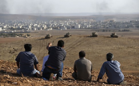 Smoke rises in the Syrian town of Kobani as Turkish Kurds watch near the Mursitpinar crossing on the Turkish-Syrian border. Photo: Reuters